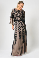 Elva sequin maxi dress with black leaf motif embellishment on a neutral base, batwing sleeves and flowing silhouette for statement occasion wear styling
