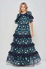 Jasmine navy maxi dress by Frock and Frill with floral embroidery, ruffled tiered skirt, and sheer flutter sleeves, styled for weddings and garden parties.