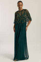 Green embellished maxi dress with flowing pleated skirt and detachable sheer cape overlay, featuring gold bead detailing and an elegant V-neck silhouette for occasion wear.