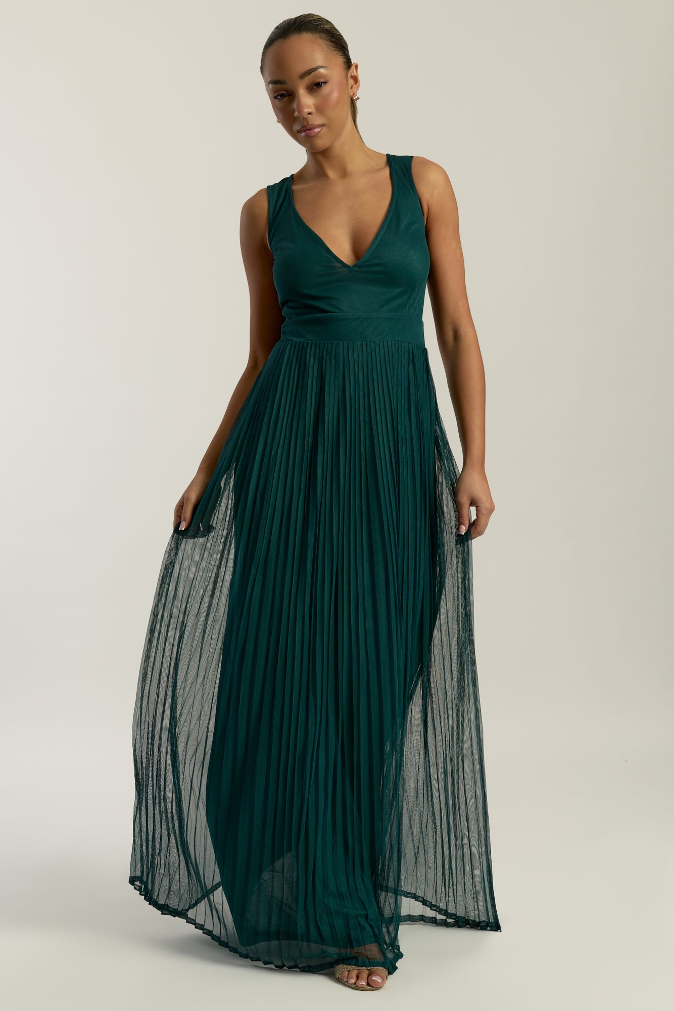 Green embellished maxi dress with flowing pleated skirt and detachable sheer cape overlay, featuring gold bead detailing and an elegant V-neck silhouette for occasion wear.